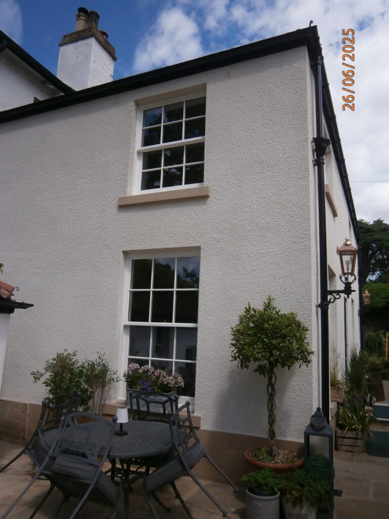 Two sliding sash windows on the exterior of a white house.